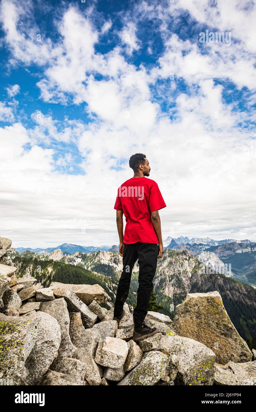 Ein junger Mann auf dem Granite Peak in den Washington Cascades mit Blick auf die Aussicht. Stockfoto