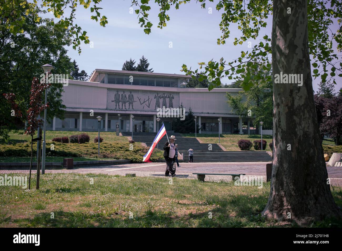 Belgrad, Serbien, 4. Mai 2022: Ein Mann mit der jugoslawischen Flagge vor dem Museum für jugoslawische Geschichte (Muzej Jugoslavije) Stockfoto