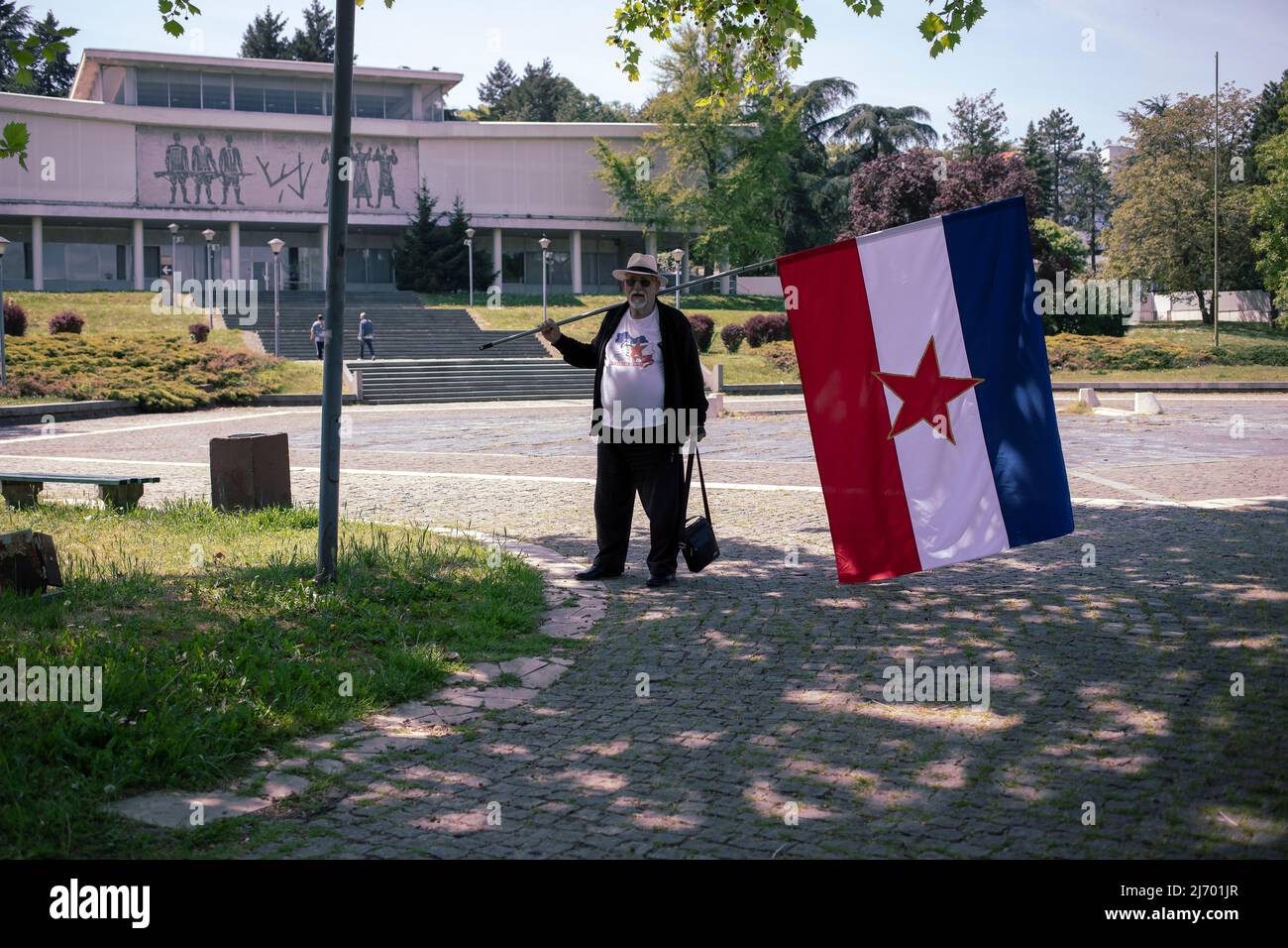Belgrad, Serbien, 4. Mai 2022: Ein Mann mit der jugoslawischen Flagge vor dem Museum für jugoslawische Geschichte (Muzej Jugoslavije) Stockfoto