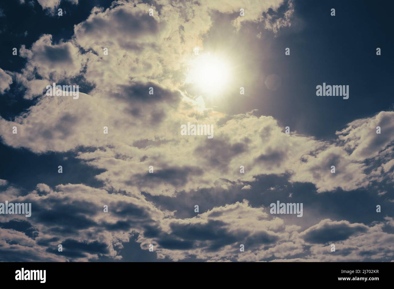 Die Sonne späht hinter den Kumuluswolken aus. Ängstliche Stimmung. Stockfoto