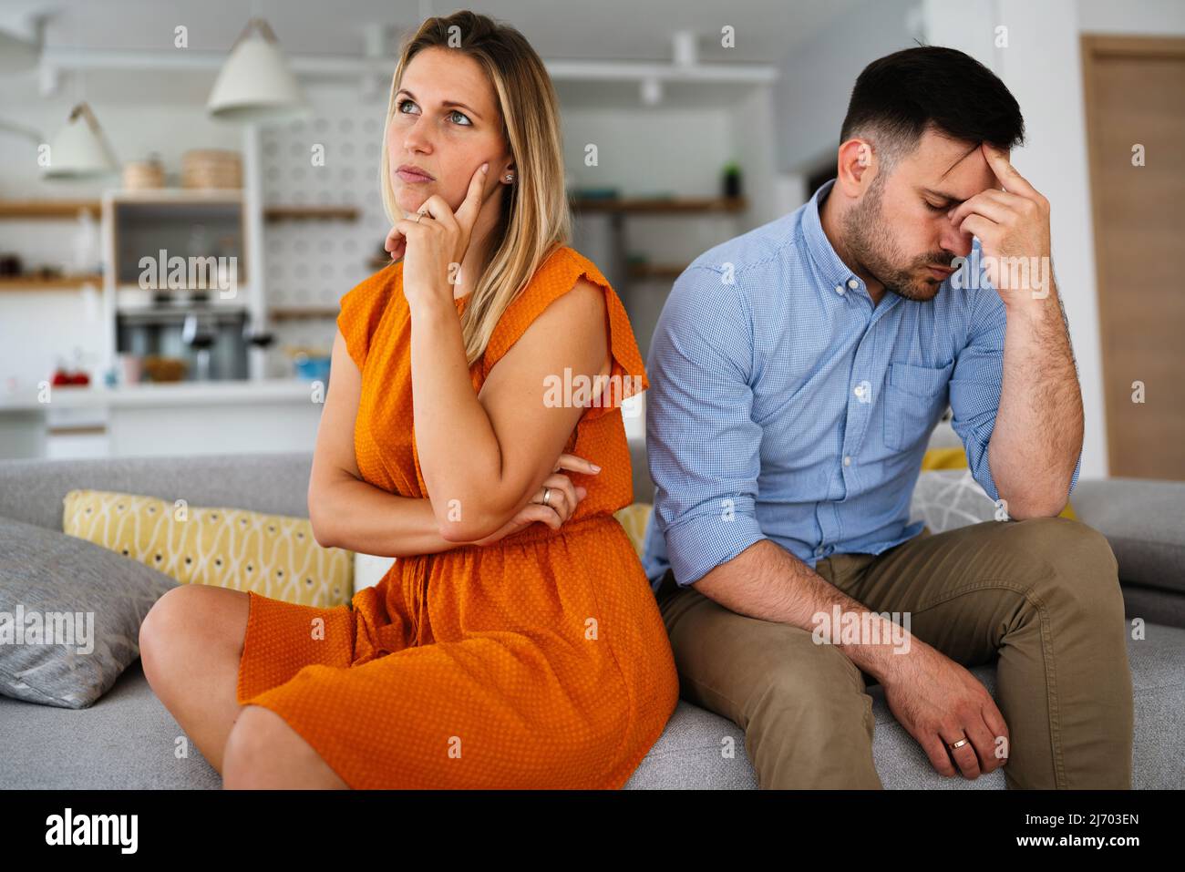 Traurige, nachdenkliche Paare, die an Beziehungsprobleme denken, die auf dem Sofa sitzen, Konflikte in der Ehe. Stockfoto