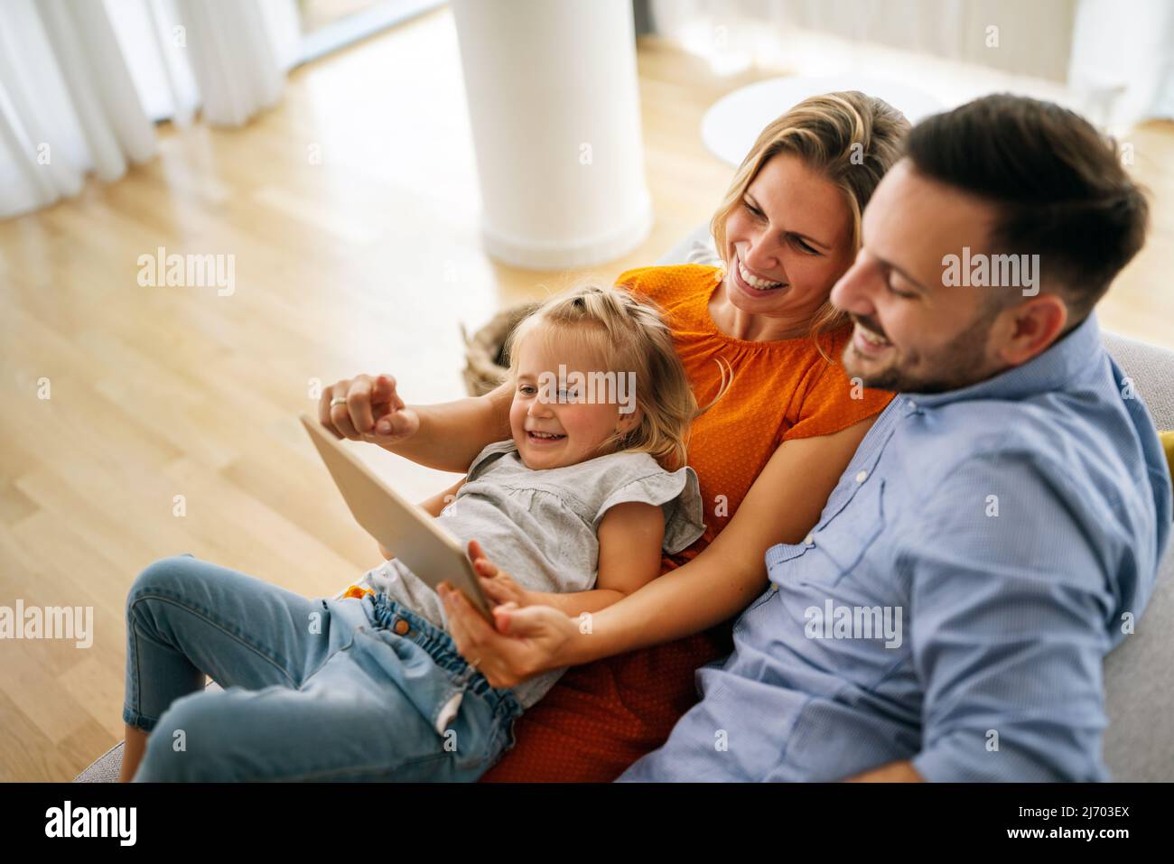 Glückliche junge Familie, die Spaß zu Hause hat. Eltern mit Kindern, die ein digitales Gerät verwenden. Stockfoto