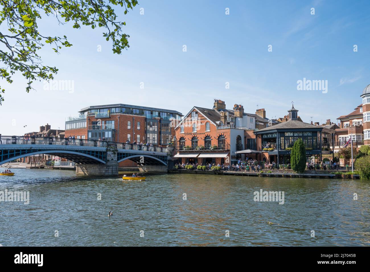 Blick über die Themse in Richtung Windsor Bridge und Cote Brasserie auf der Eton-Seite. Leute essen auf der Terrasse am Fluss. Windsor, England, Großbritannien Stockfoto