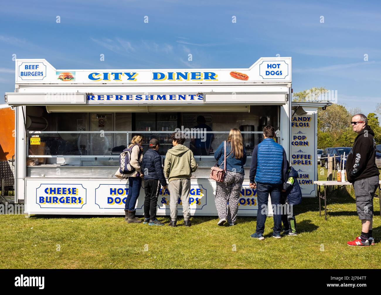Kunden, die Schlange stehen, um den Burger- und Erfrischungsanhänger beim lokalen Autozuchtwagenverkauf, Hertfordshire England, anzustellen Stockfoto