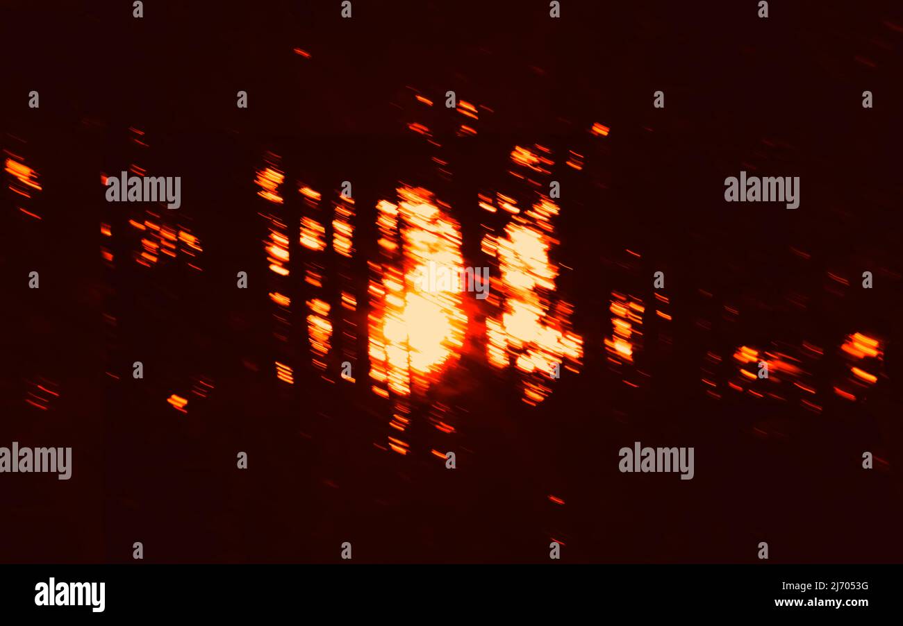 Abstrakter Hintergrund mit dunklen Bewegungen und verwischten roten Lichtern, hellen Flecken. Langzeitbelichtung. Stockfoto