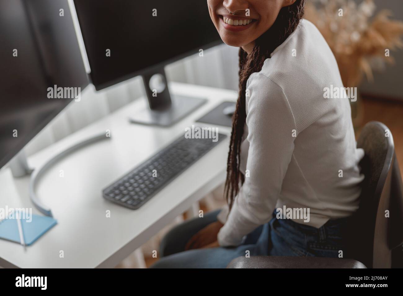 Nahaufnahme einer nicht erkennbaren jungen positiven Frau in der Halle am Tisch mit Computermonitoren Stockfoto