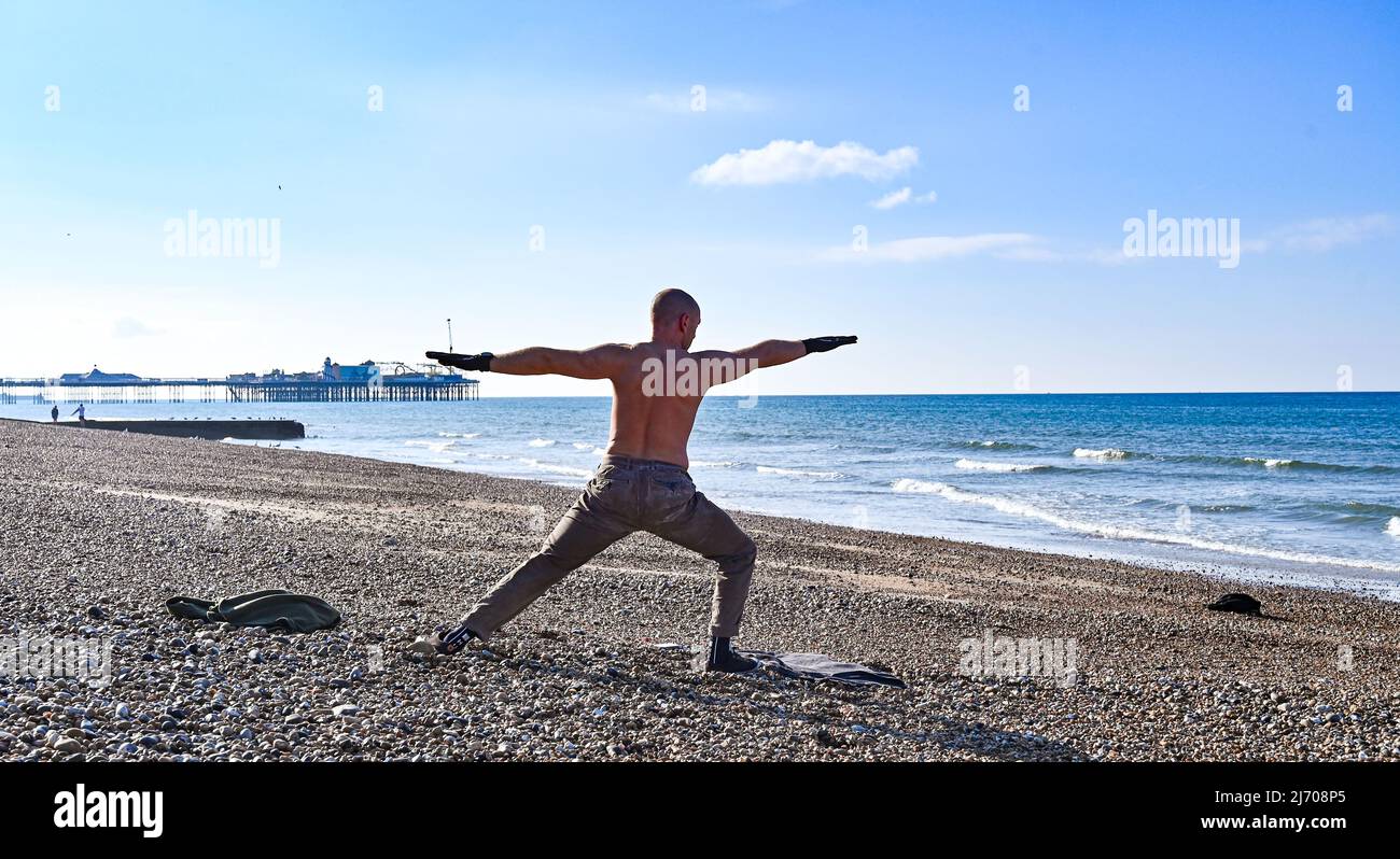 Brighton UK 5. May 2022 - Es ist ein schöner sonniger Morgen am Brighton Beach für einige Yoga-Übungen, da die Temperaturen heute in einigen Teilen des Südostens über 20 Grad erreichen werden : Credit Simon Dack / Alamy Live News Stockfoto
