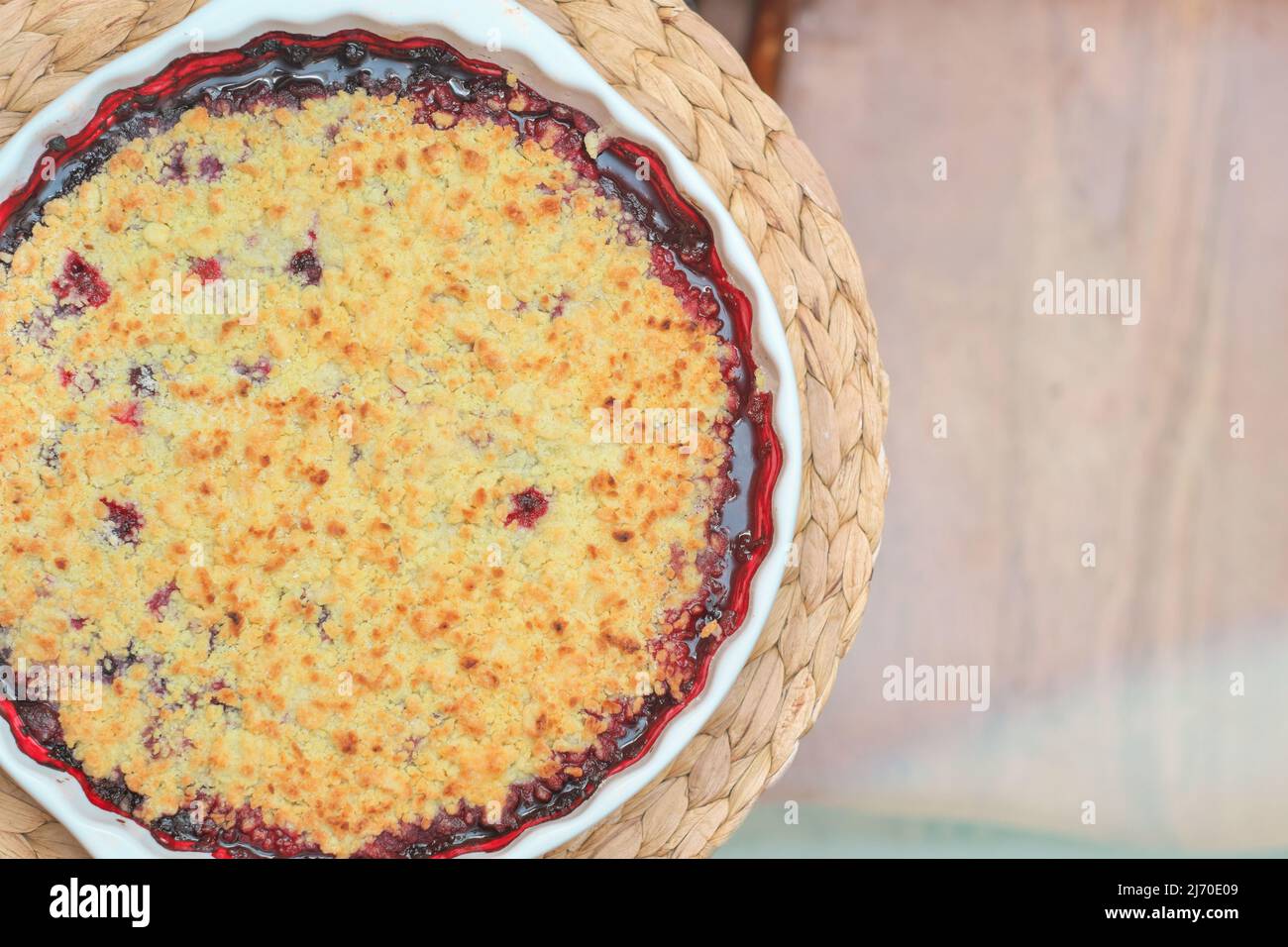 Runde Beerenkuchen in Backform auf Tischset. Bröseln Heidelbeer Schuster. Hausbacken, gesunde Mahlzeit, zuckerfreies Essen Stockfoto