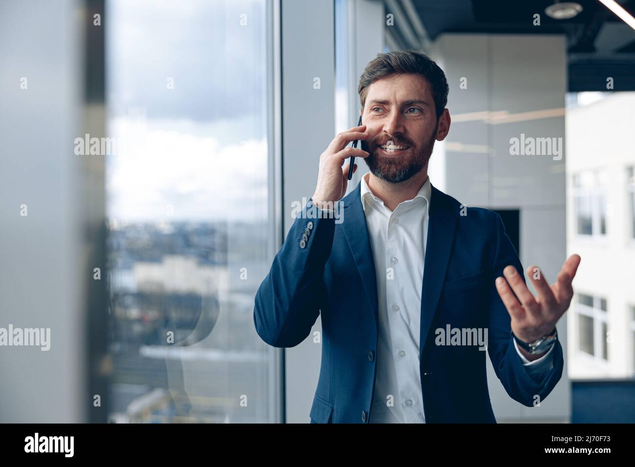 Porträt eines inspirierten Mannes, der sein Mobiltelefon benutzt und seinen Geschäftspartner im Büro anruft Stockfoto