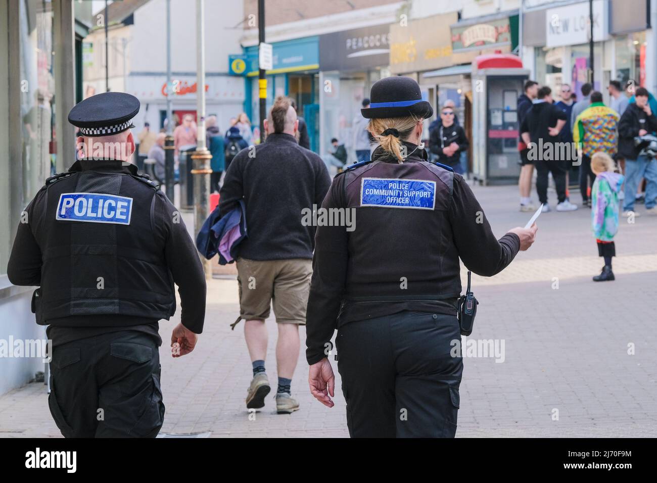 Ein Polizeibeamter und ein Unterstützungsbeamter der Polizeigemeinde, die durch das Stadtzentrum von Newquay in Cornwall im Vereinigten Königreich gehen. Stockfoto