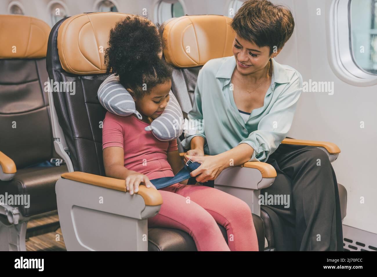Kinder in der Flugkabine legen den Sicherheitsgurt an, um Urlaub mit der Mutter zu machen Stockfoto