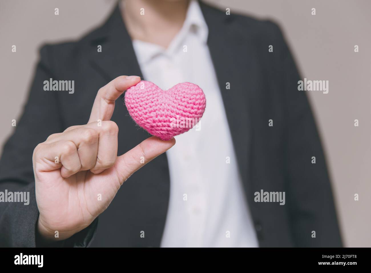 Geschäftsperson, die Herz zeigt, singt für den Austausch von Liebe und Fürsorge bei der Arbeit Stockfoto