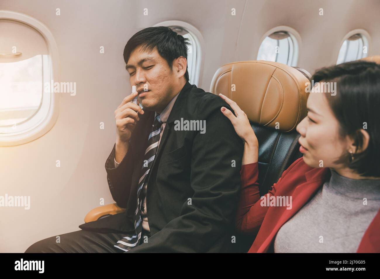 Asiatischer Geschäftsmann männliche Bewegung krankes Gesundheitsproblem während des Fluges an Bord in der Flugkabine. Stockfoto