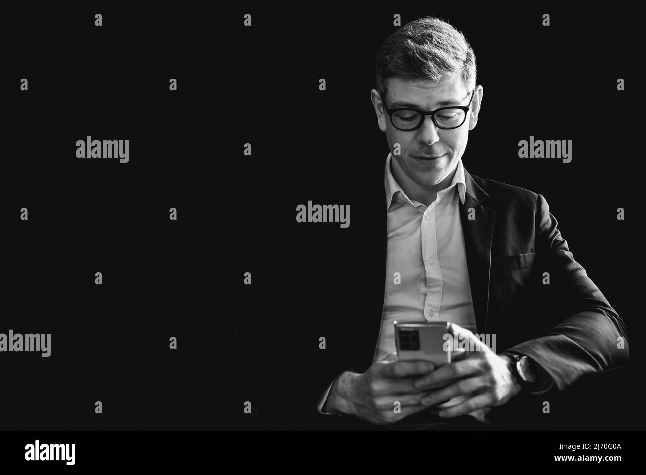 Geschäftsmann, der im Schatten denkt, liest Geschäftsinformationen auf dem Smartphone-Bildschirm mit Kopierfläche und weißem Vintage-Ton. Stockfoto