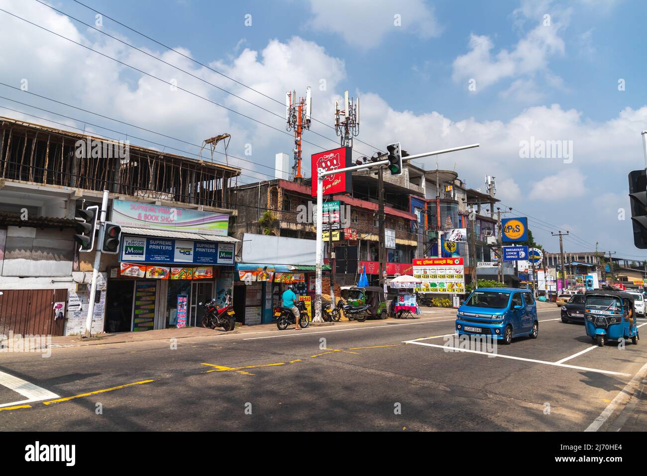 Malabe, Sri Lanka - 4. Dezember 2021: Blick auf die Straße mit Autos, Motorroller und Tuk Tuks. Gewöhnliche Menschen gehen die Straße entlang Stockfoto