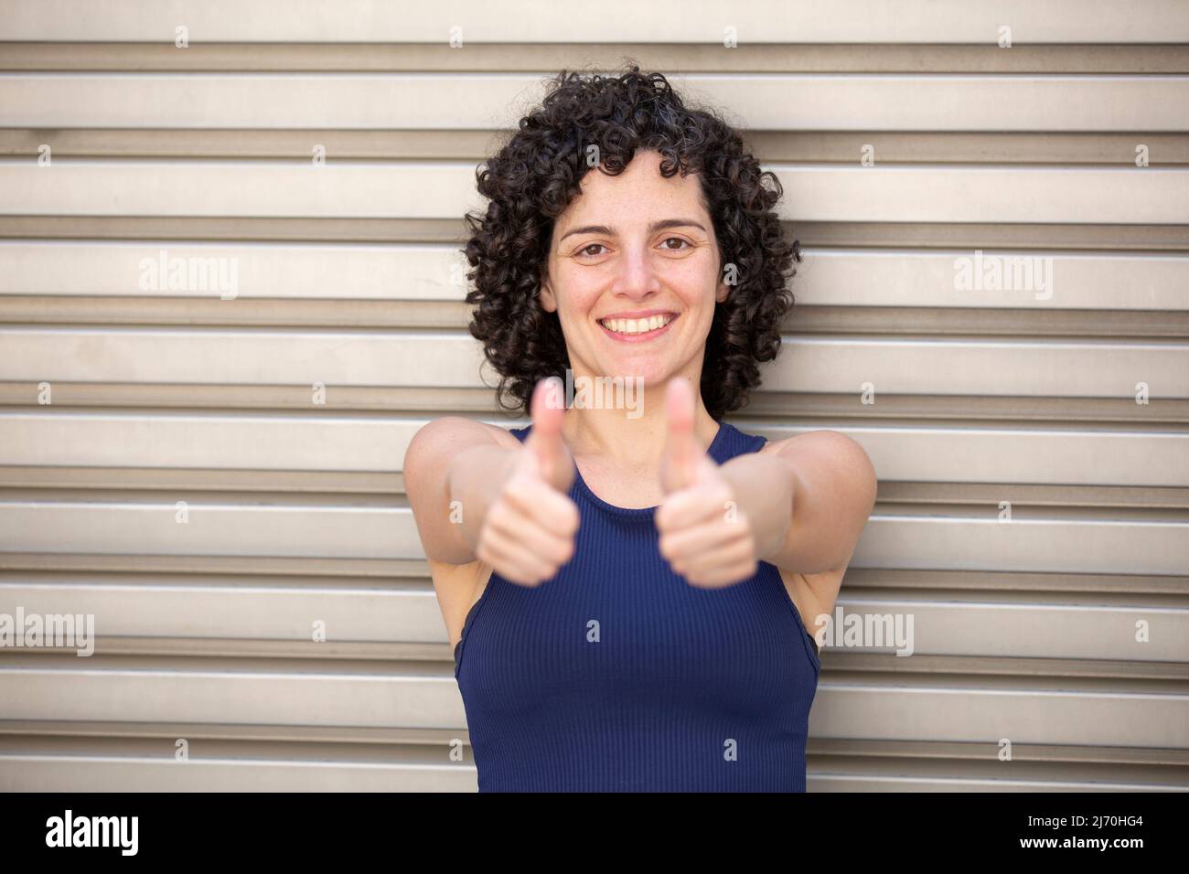 Schöne Frau lächelt und zeigt Daumen nach oben Geste im Freien Stockfoto