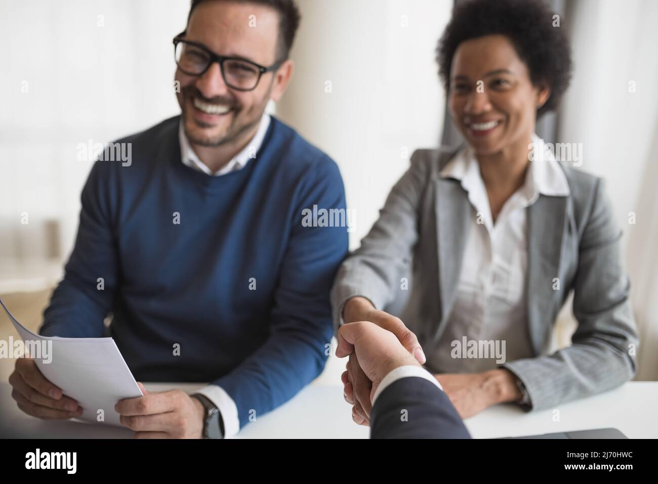 Glückliche Geschäftspartner, die in Meetings Handschlag geben, lächelnde Berufstätige, die am Schreibtisch sitzen, feiern einen erfolgreichen Abschluss bei cor Stockfoto