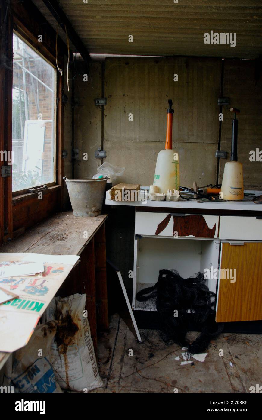 Das schmuddelige Innere des nicht mehr genutzten Betonblockschuppens mit Asbestdach wird kurz vor dem Abriss stehen Stockfoto