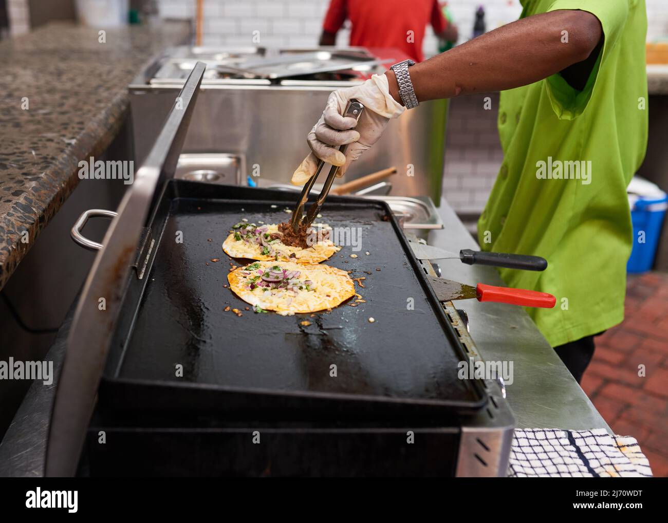 Ein Chefassistent legt gezogenes Rindfleisch auf einen Taco auf dem Grill Stockfoto