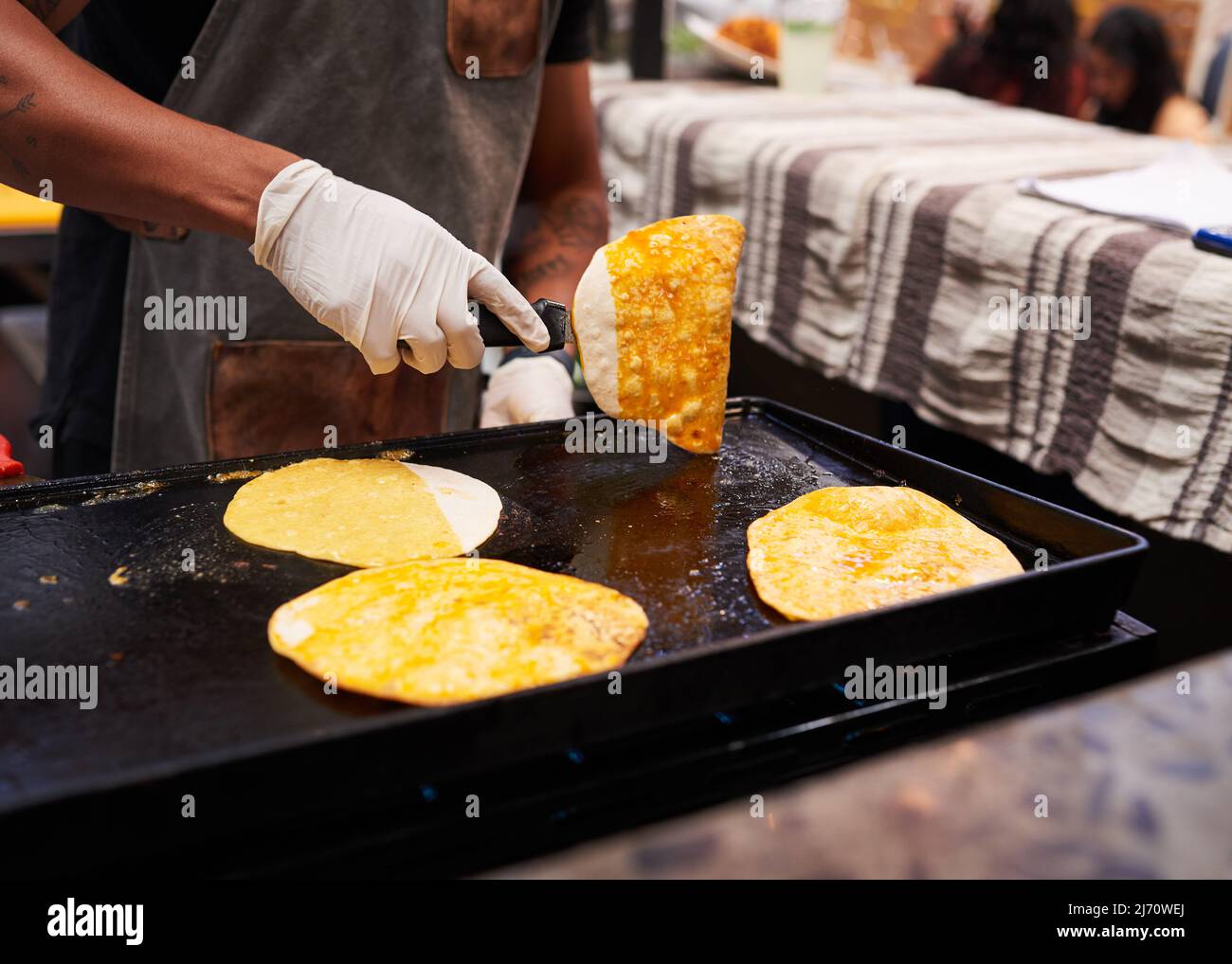Nahaufnahme der Hände, die auf einem Markt ein Taco auf einem Grill drehen Stockfoto