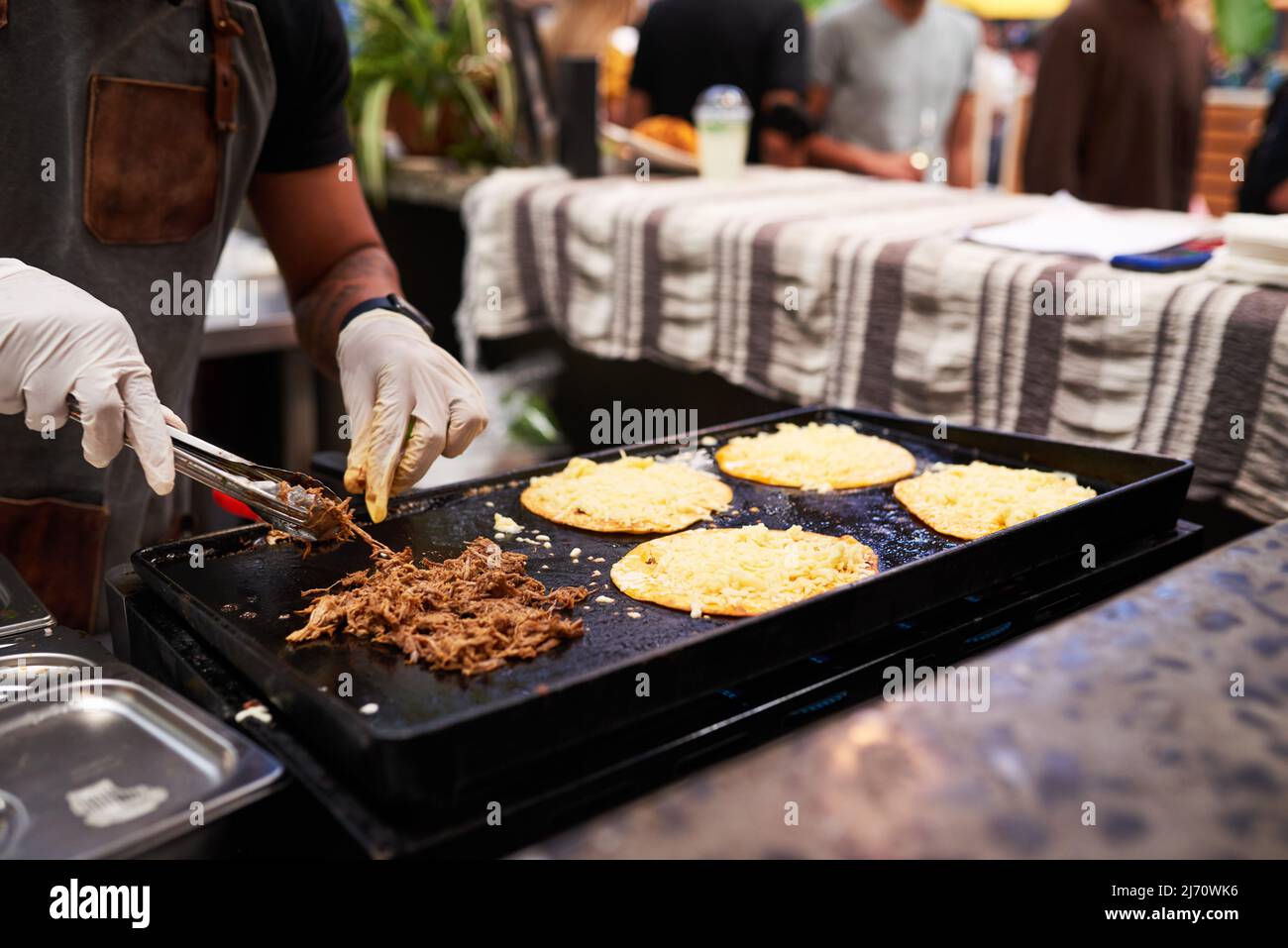 Ein Mann grillt Rindfleisch und Käse Tacos auf einem Markt, Nahaufnahme Hände Stockfoto