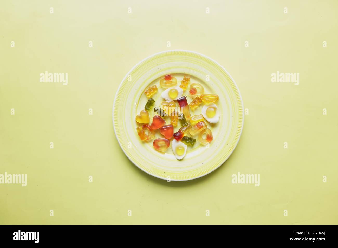 Gummy Bonbons auf einem Teller auf gelbem Hintergrund. Stockfoto