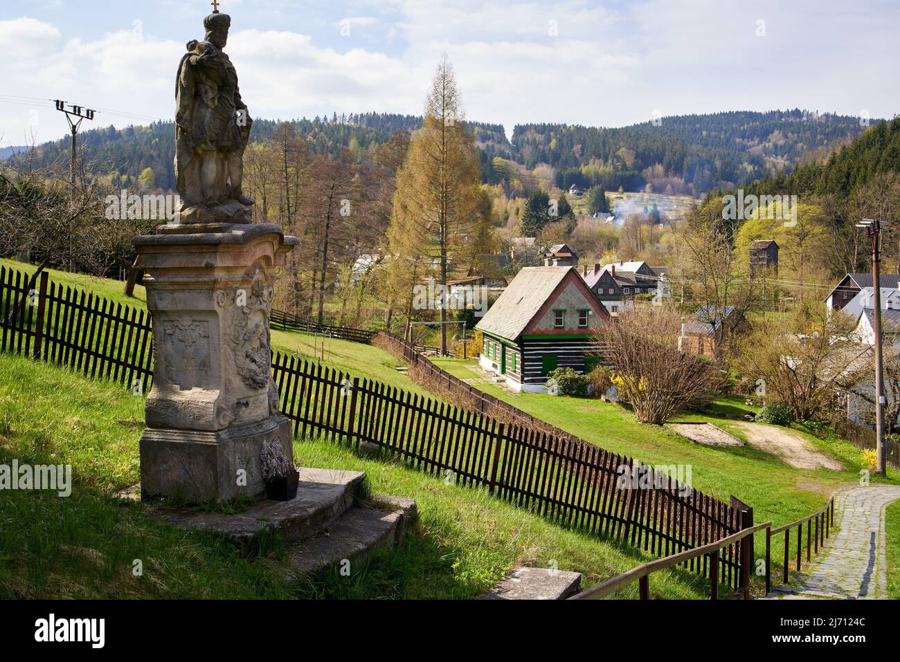 KRYSTOFOVO UDOLI, TSCHECHISCHE REPUBLIK - 29. APRIL 2022: Barocke Statue vor einem romantischen Dorf im Isergebirge Stockfoto
