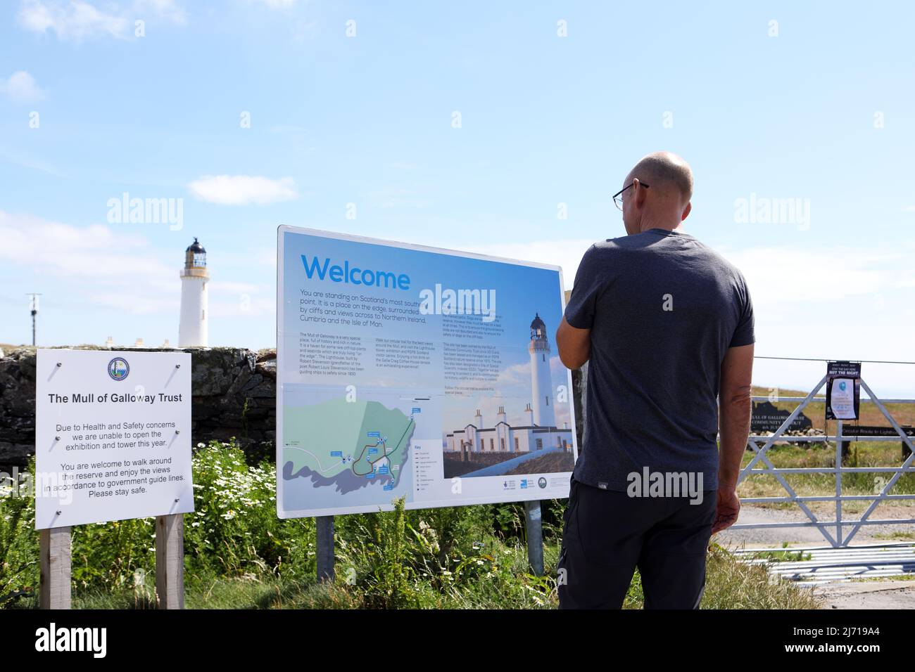 Mann liest die Informationstafel des Mull of Galloway Lighthouse, der am südlichsten Punkt Schottlands steht. Stockfoto