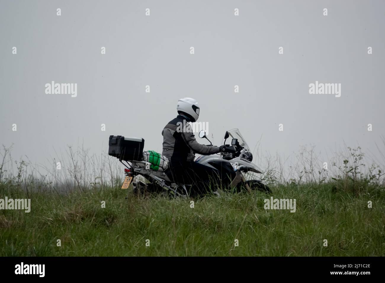 Motorradfahrer auf einem weißen BMW R1200, der durch die Frühlingslandschaft reist Stockfoto