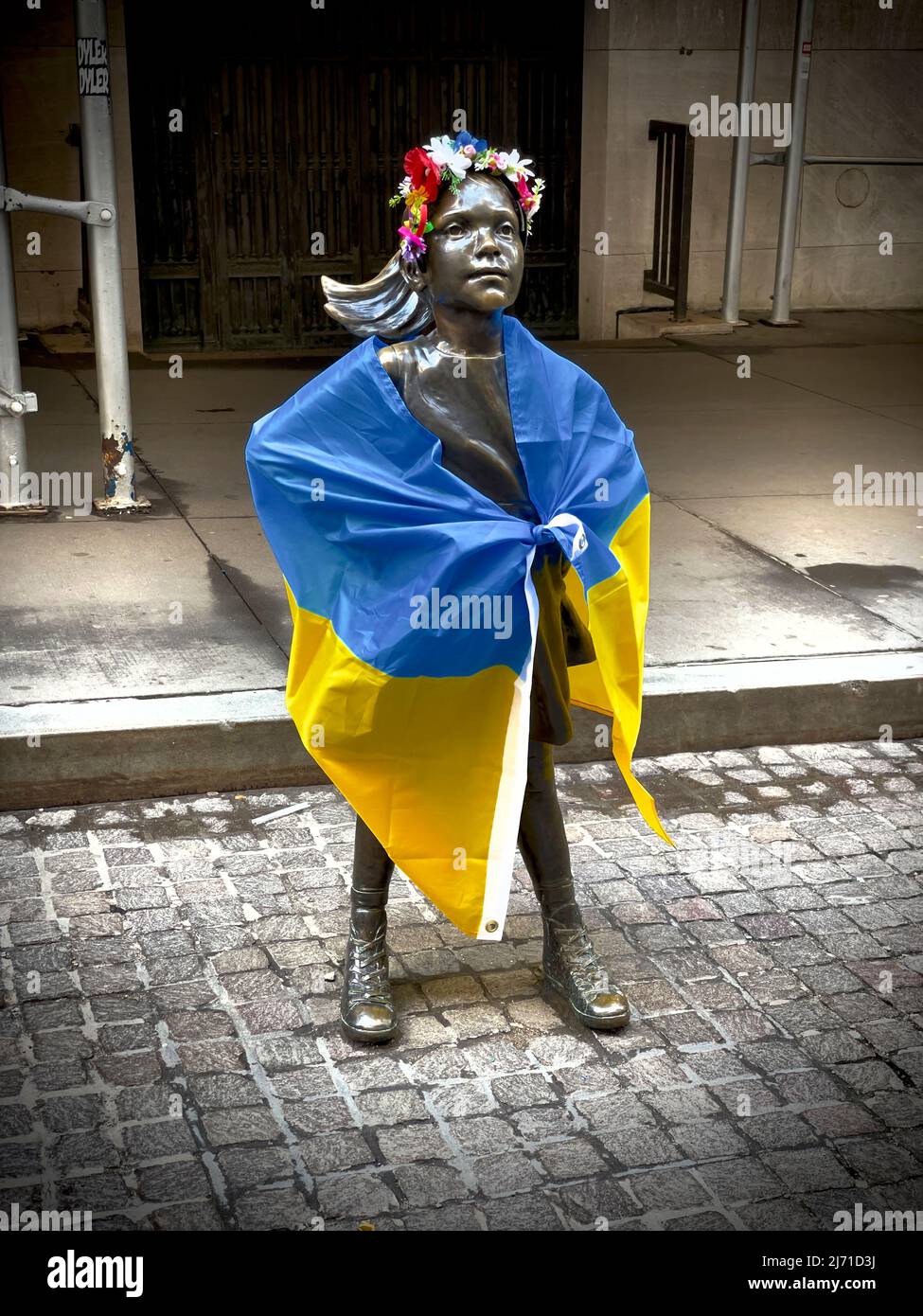 Fearless Girl Statue drapiert mit ukrainischer Flagge und traditionellem Kopfkleid. Gegenüber der New Yorker Börse in New York City gelegen. Stockfoto