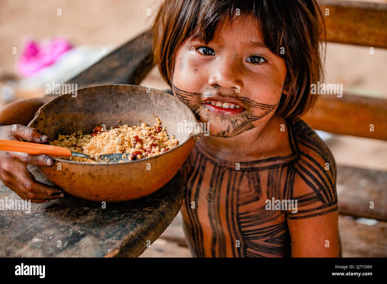 Schönes indigenes Kind aus dem indianerstamm Asurini im Amazonas, das aus einer Holzschüssel eine Mahlzeit aus Cassava-Mehl isst. Baixo Amazonas, Brasilien 2010. Stockfoto