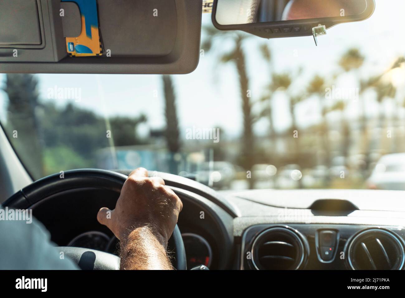 Das Auto fährt entlang einer gepflegten Straße an Palmen vorbei. Blick durch die Windschutzscheibe. Stockfoto