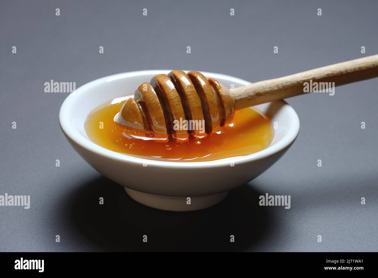 Bienenhonig mit Honiglöffel in Schüssel, Blütenhonig Stockfoto