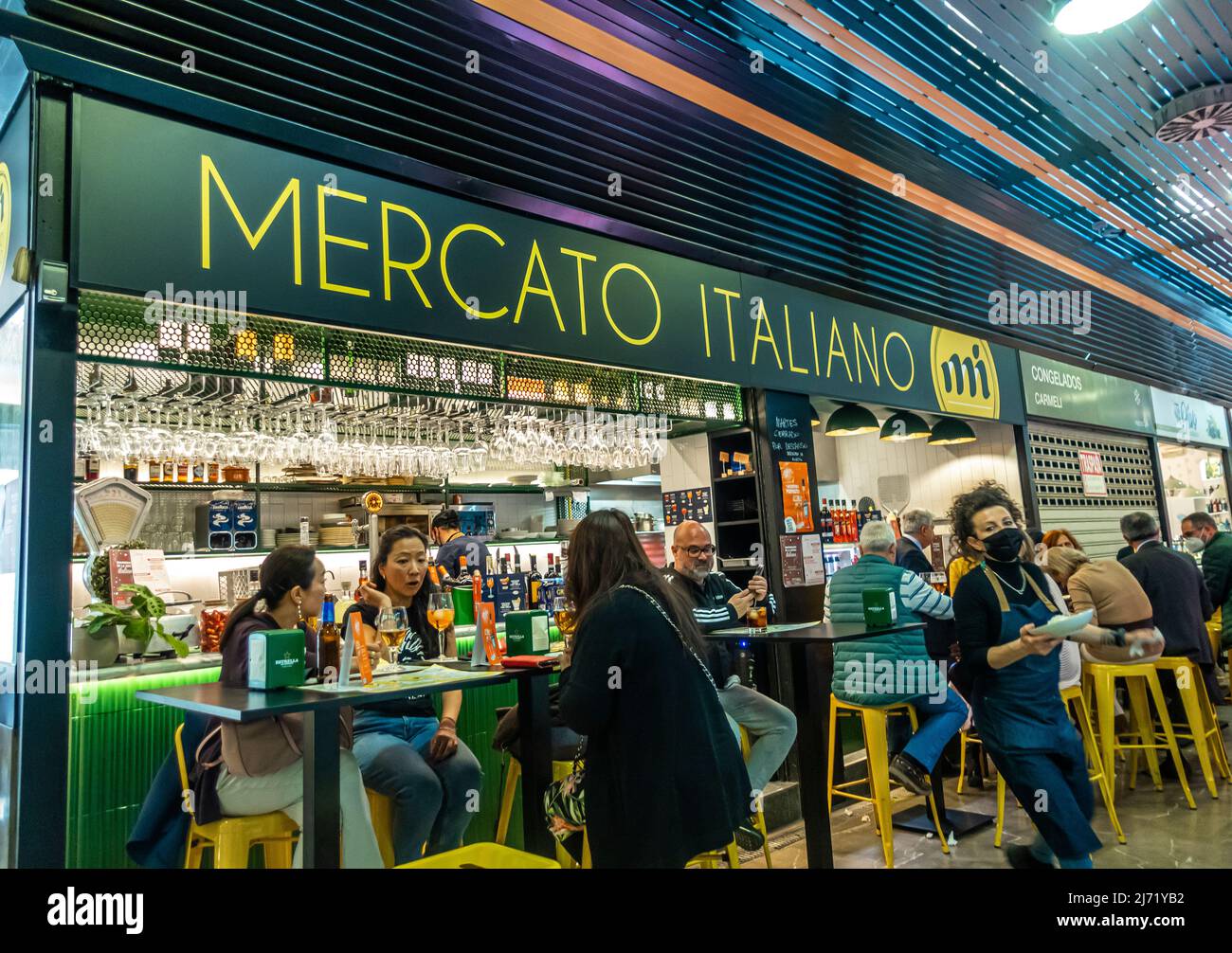 Mercato Italiano - Italienischer Marktplatz innerhalb des spanischen Marktes - Mercado de San Agustín. Kellner mit Gesichtsmasken serviert Gästen Essen und Trinken Stockfoto