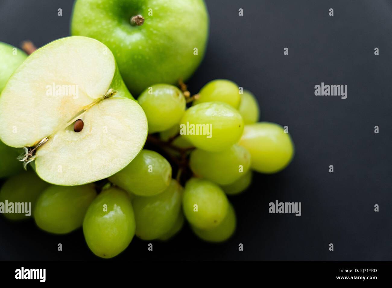 Draufsicht auf Apfelhälfte oben auf Trauben auf Schwarz Stockfoto