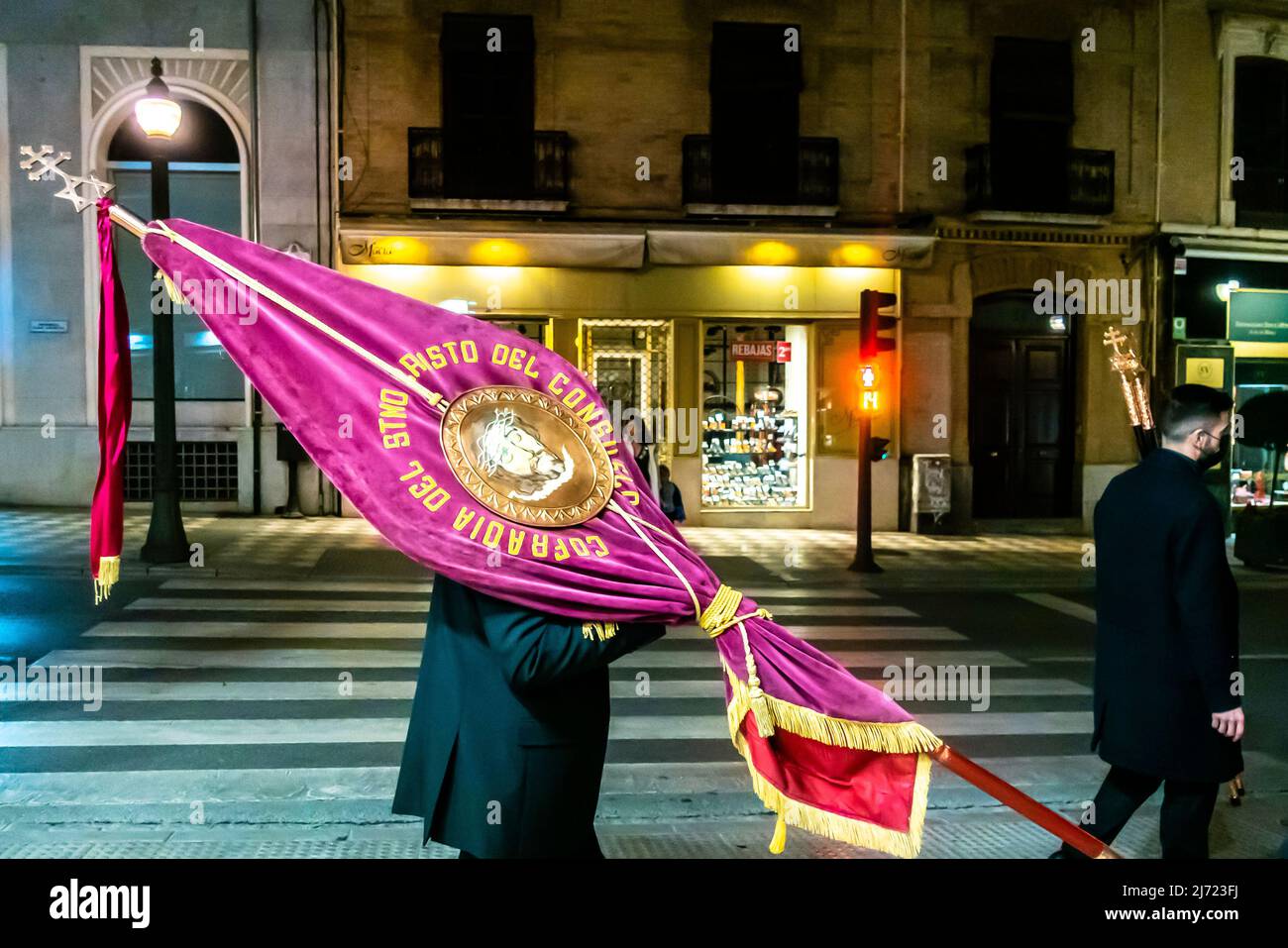 Priester Minister von Cofradía del Stmo. Cristo del Consuelo trägt Flagge in den Straßen von Granada in der Nacht. Spanien Stockfoto