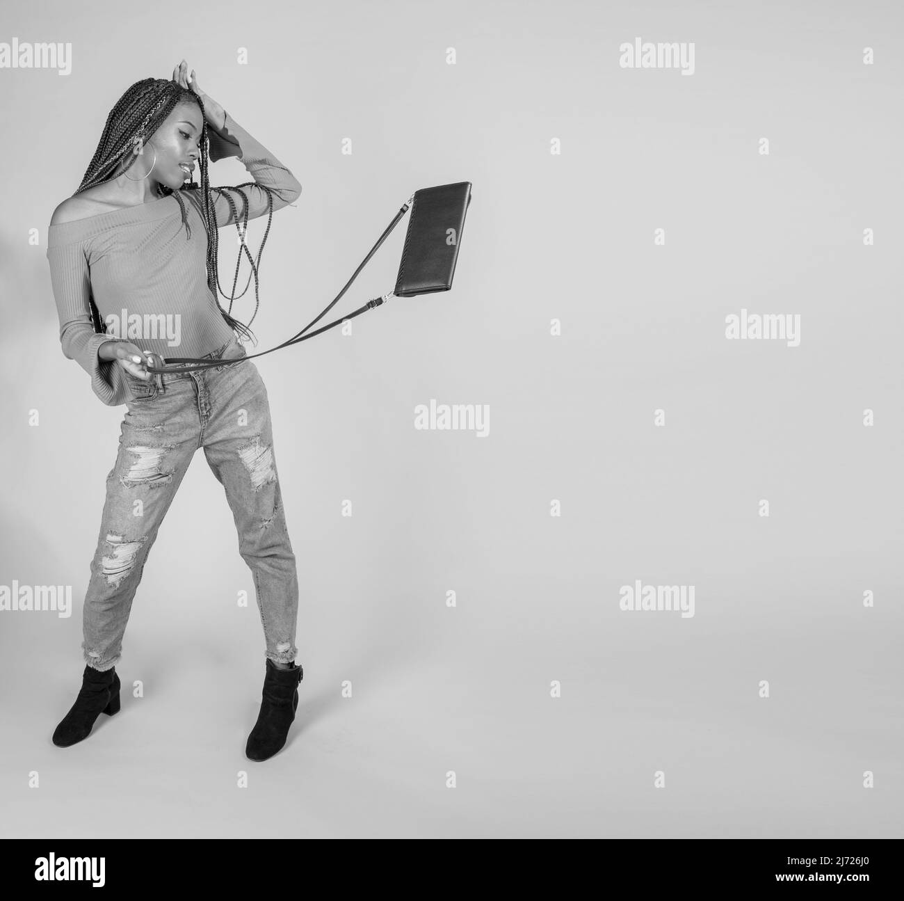 Studio shot einer jungen schwarzen Frau mit Vintage orange oben und Baggy Jeans auf einen weißen Hintergrund mit den Geldbeutel posing Stockfoto