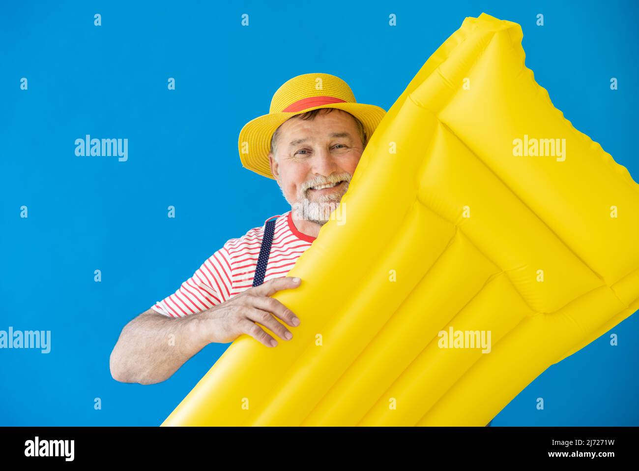 Glücklicher älterer Mann, bereit zu reisen. Person mit gelber Luftmatratze. Sommerurlaub und Urlaubskonzept Stockfoto