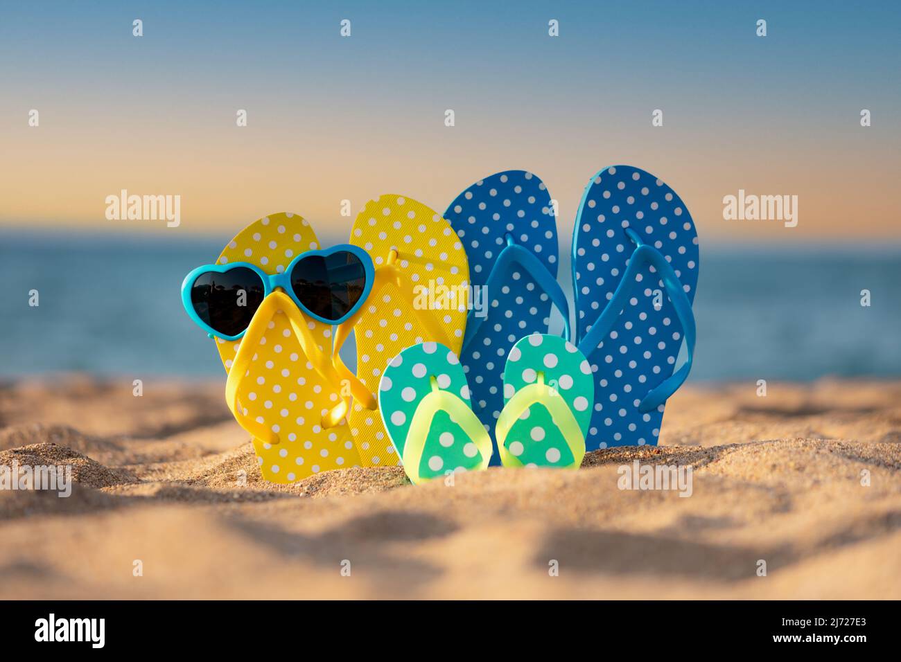 Strandflipflops auf dem Sand gegen Meer- und Himmelshintergrund. Konzept für Sommerferien Stockfoto