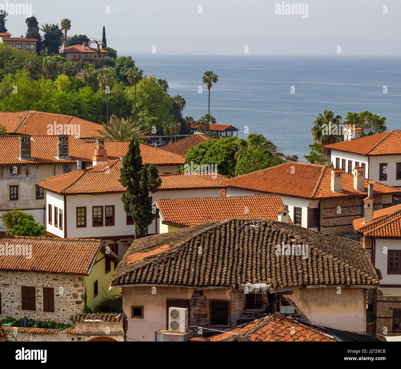 Alte Stadthäuser mit grünen Bäumen, blauem Himmel, Meeresboden. Atemberaubender Blick auf mediterrane Altstadthäuser. Stockfoto