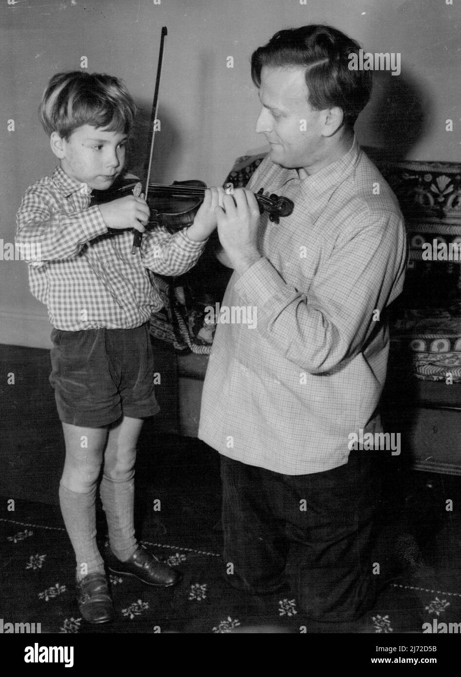 Er sollte gut auf dieser Violine sein -- Wenn er seinem Vater nachgeht. Der junge Mann mit der Violine ist der 6-jährige Gerard Menuhin, Sohn des weltberühmten Geigers Yehudi Menuhin. Vater gibt Gerard einen Geigenunterricht in ihrem Londoner Hotel. Yehudi Menuhin ist hier, um Rezitale zu geben. 12. Dezember 1954. (Foto von Paul Popper, Paul Popper Ltd.). Stockfoto