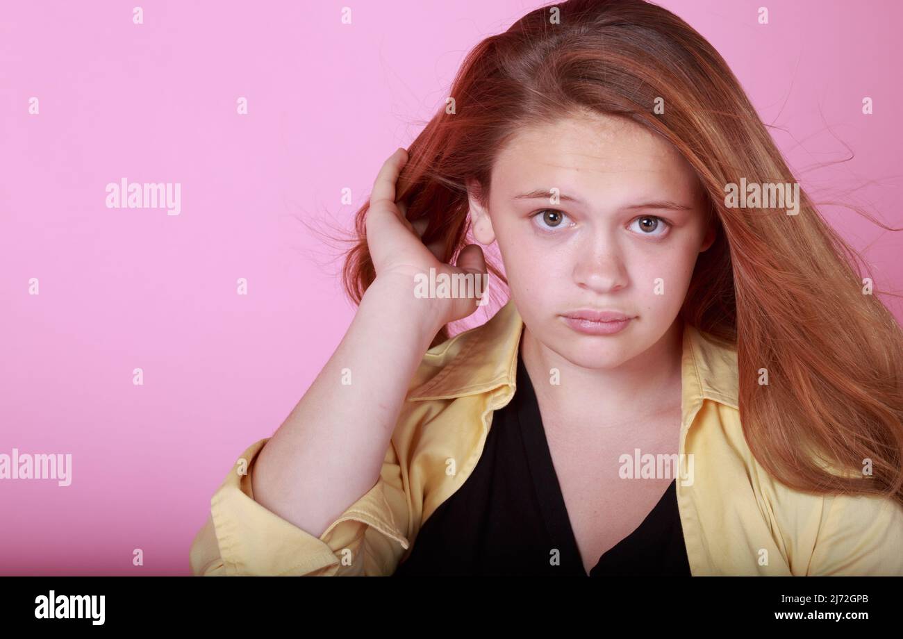 Ernst süße Rothaarige jugendlich Mädchen auf einem rosa Hintergrund posiert Stockfoto