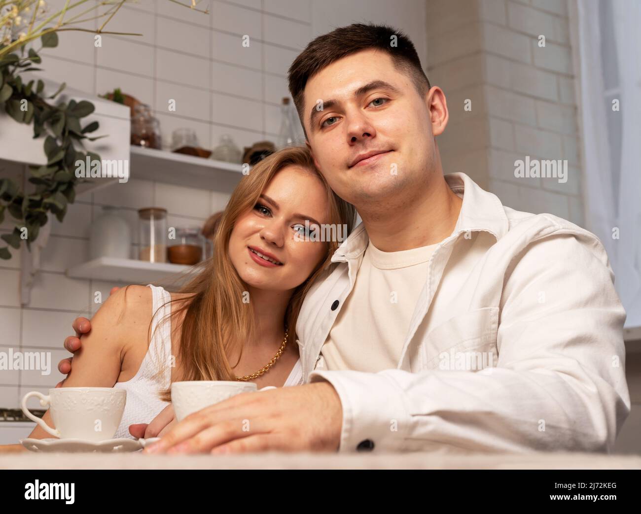 Familienportrait der Liebe Paar von Mann und Frau sitzen zu Hause Esstisch, umarmt, Blick auf die Kamera. Stockfoto