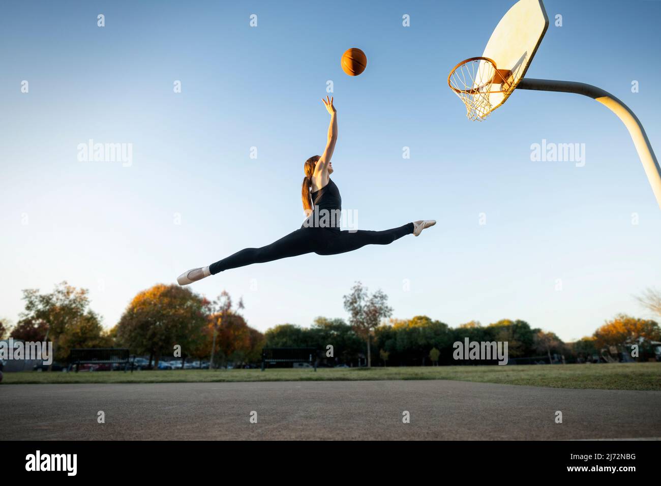 Balletttänzerin schießt Körbe auf einem Basketballplatz im Freien Stockfoto