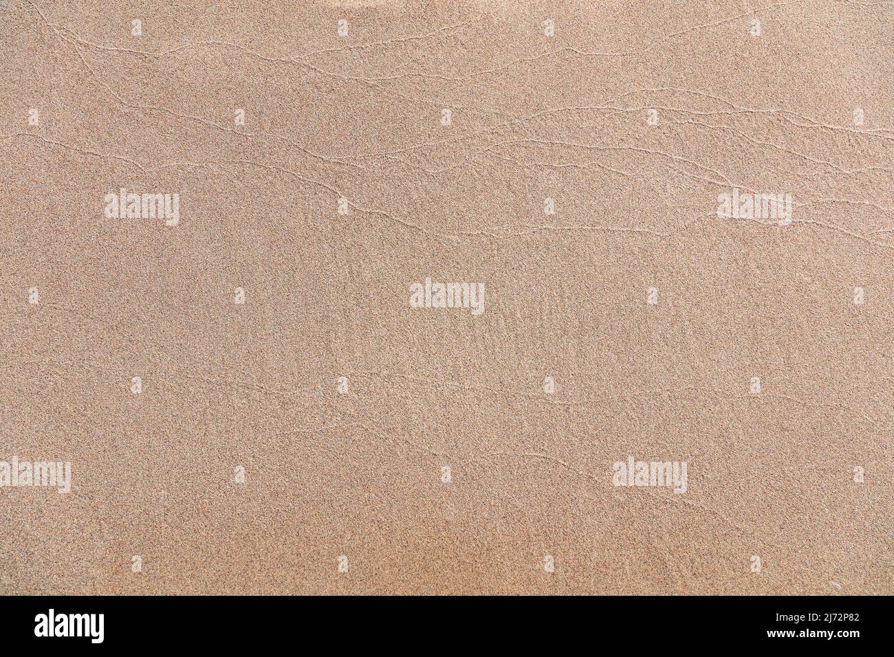 Leerer nasser Sand Textur Hintergrund. Sandstrand in Griechenland, Nahaufnahme von oben. Meerwasser nivellierte Oberfläche, kopieren Raum. Griechische Insel, Sommerurlaubstemperatur Stockfoto