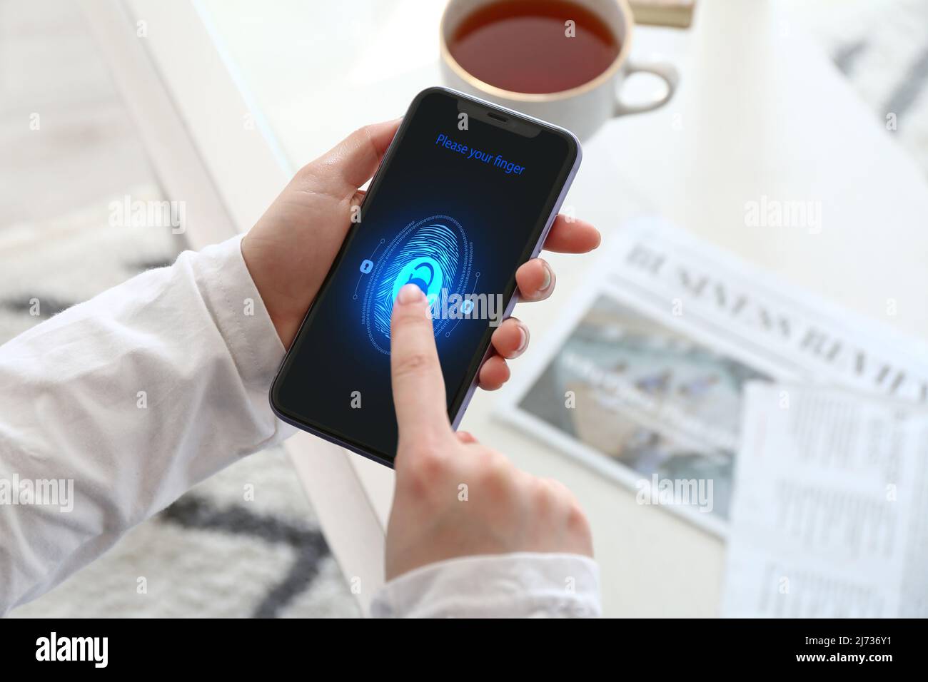 Frau mit Smartphone, die Fingerabdruckscanner verwendet, um sich bei einem persönlichen Konto anzumelden Stockfoto