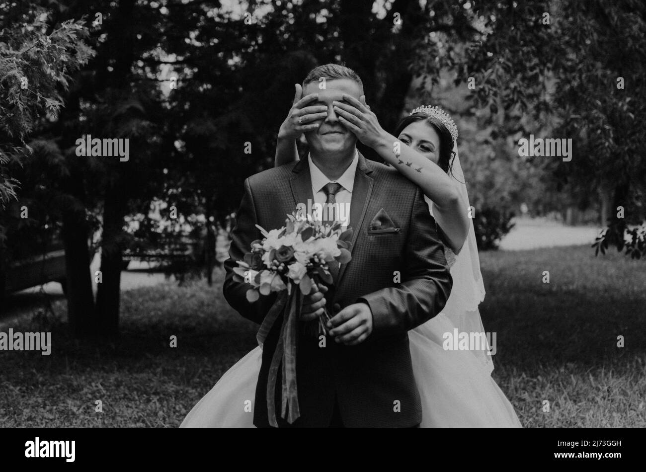 Europäische kaukasischen Mann Bräutigam in Anzug und Frau Braut im Hochzeitskleid Schleier Tiara auf dem Kopf. Erste Sitzung Brautpaar warten sieht Braut. Mädchen kommt Stockfoto