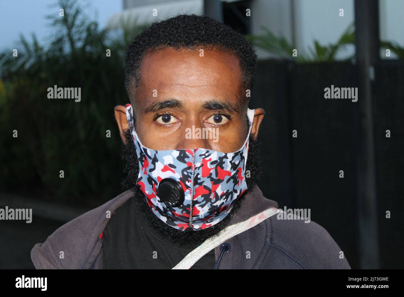 Ein junger Mann aus Papua-Neuguinea trägt eine Gesichtsmaske auf dem Internationalen Flughafen von Jackson in Papua-Neuguinea Stockfoto