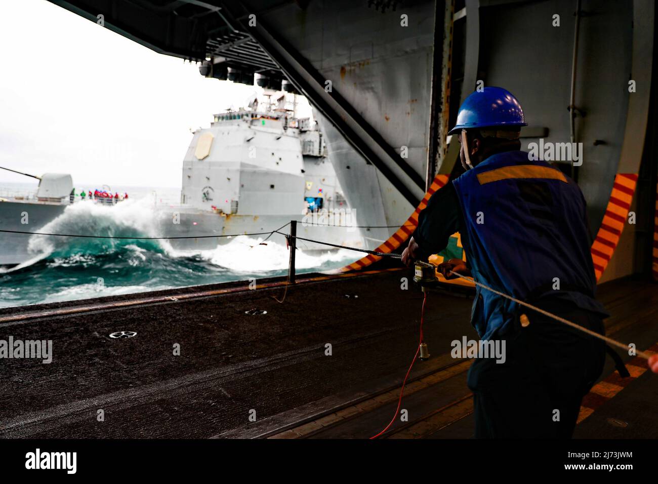 SEA OF JAPAN (14. April 2022) Mate Seaman Benjamin Suazo von Boatswain aus Bronx, N.Y., wickelt die Linie in der Hangarbucht des Flugzeugträgers USS Abraham Lincoln (CVN 72) der Nimitz-Klasse während einer Betankung auf See mit dem Lenkraketen-Kreuzer USS Mobile Bay (CG 53) der Ticonderoga-Klasse ab. Die Abraham Lincoln Strike Group befindet sich im geplanten Einsatzgebiet der US-Flotte für 7., um die Interoperabilität durch Allianzen und Partnerschaften zu verbessern und gleichzeitig als reaktionsfähige Truppe zur Unterstützung einer freien und offenen Region im Indo-Pazifik-Raum zu dienen. (USA Navy Foto von Mass Communication Specialist Seaman Kassand Stockfoto