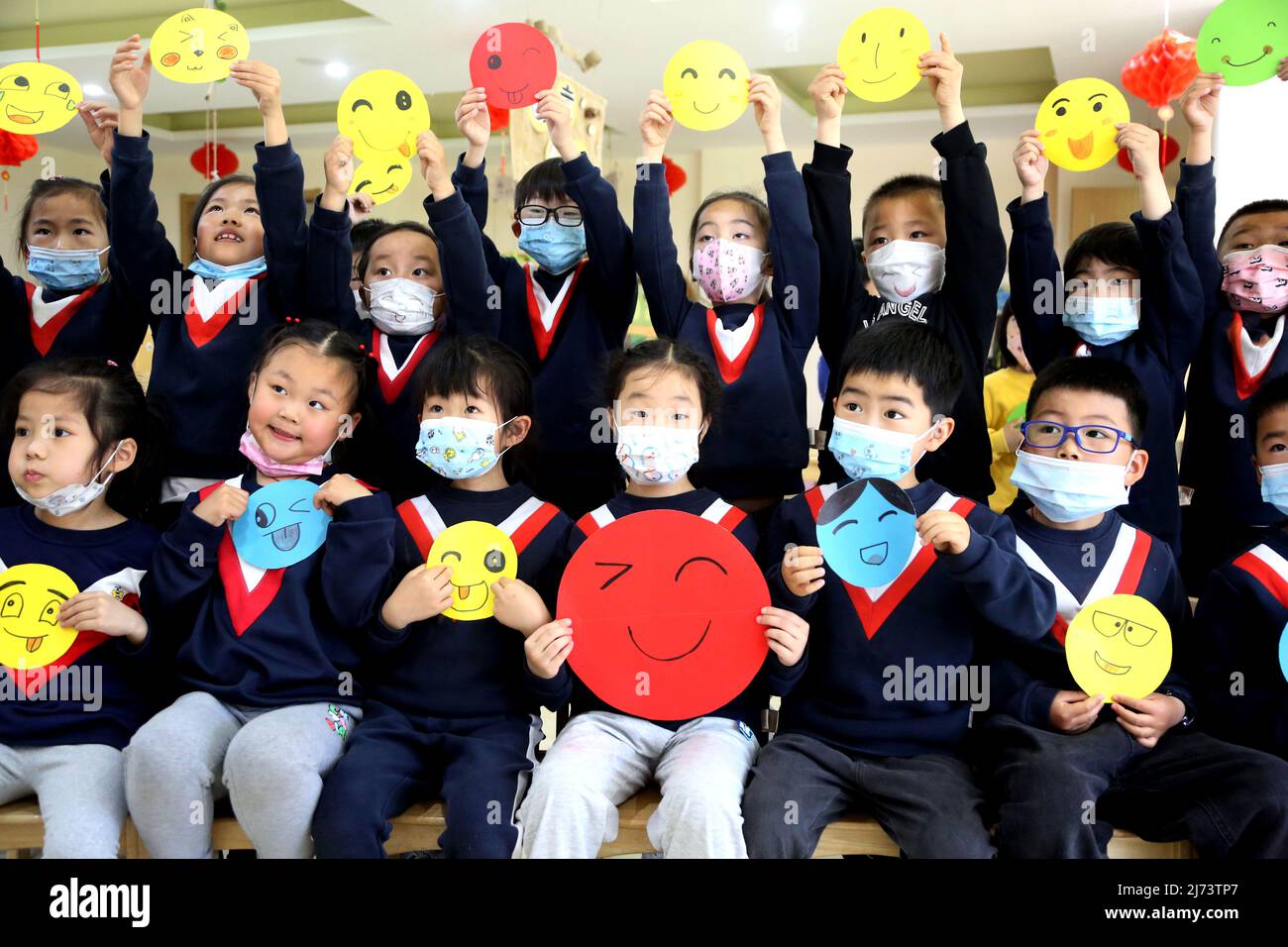 LIANYUNGANG, CHINA - 6. MAI 2022 - Kinder zeigen Bilder von lächelnden Gesichtern im Poly Hele Art Kindergarten in der Stadt Lianyungang, dem Jiangsu Pro in Ostchina Stockfoto